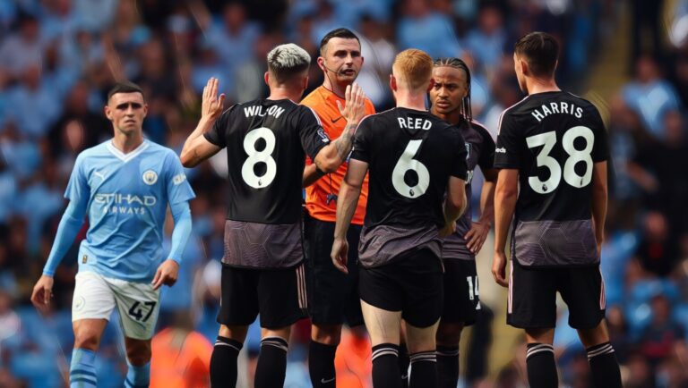 Referee Michael Oliver explains a decision to Harry Wilson and Harrison Reed of Fulham after awarding Manchester City a goal following a VAR review.