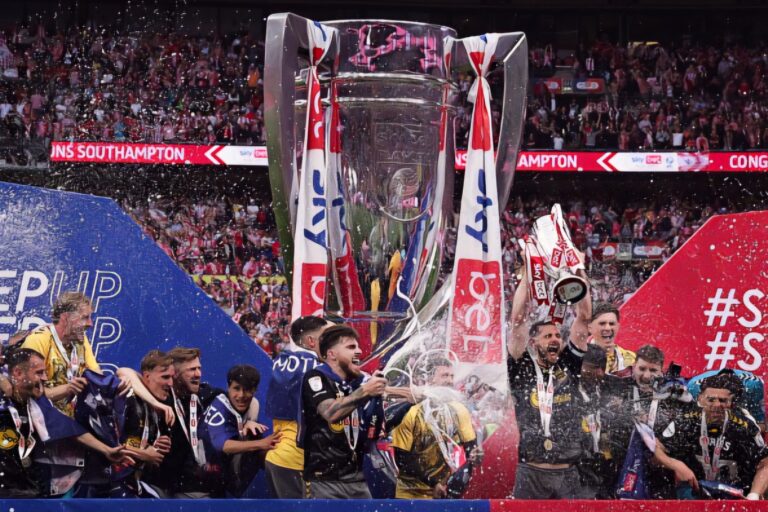 Southampton's English defender #05 Jack Stephens lifts the Championship play-off trophy up as Southampton players celebrate their win on the pitch after the English Championship play-off final football match between Leeds United and Southampton at Wembley Stadium in London on May 26, 2024.