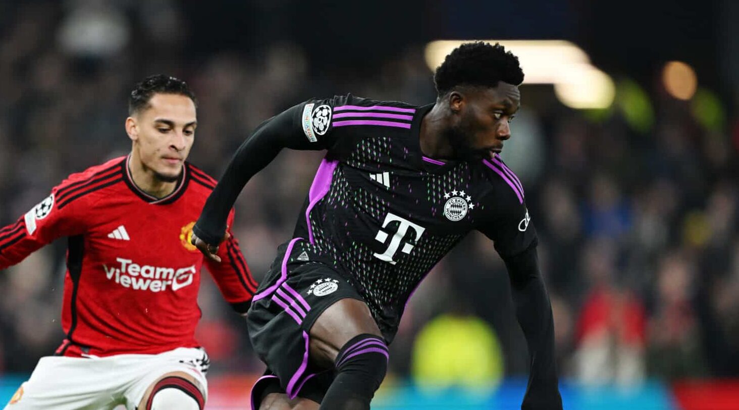 Alphonso Davies of Bayern Munich on the ball whilst under pressure from Antony of Man United during the UEFA Champions League match between Manchester United and FC Bayern München at Old Trafford on December 12, 2023 in Manchester, England.