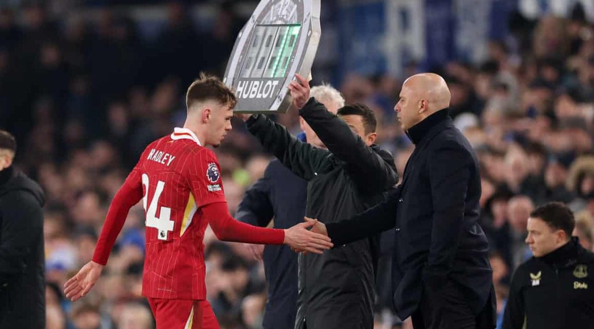 Conor Bradley of Liverpool interacts with Arne Slot, Manager of Liverpool, as he is substituted during the Premier League match between Everton FC and Liverpool FC at Goodison Park on February 12, 2025 in Liverpool, England.