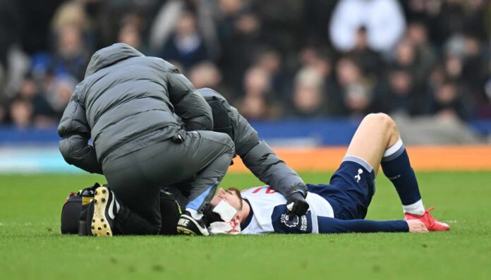 Radu Dragusin of Tottenham Hotspur receives medical treatment during the Premier League match between Everton FC and Tottenham Hotspur FC at Goodison Park on January 19, 2025 in Liverpool, England.