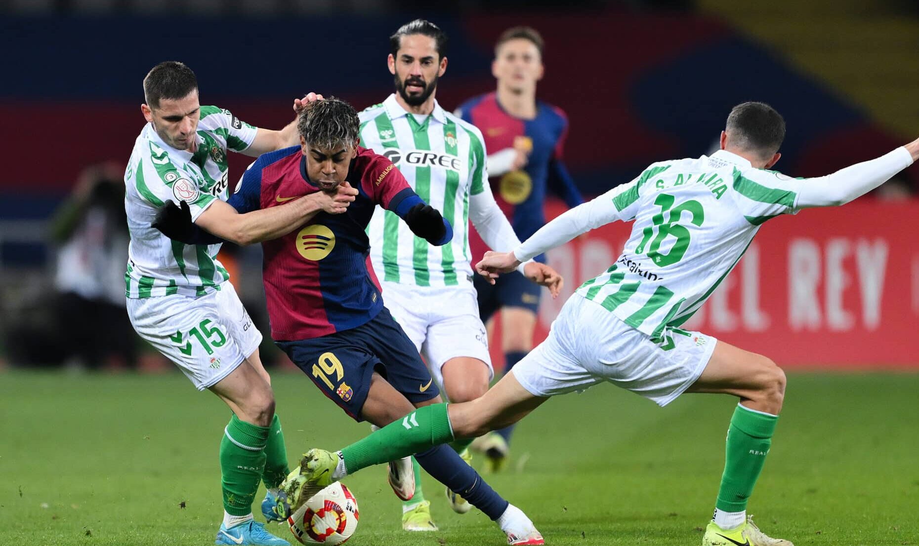 Barcelona winger Lamine Yamal runs with the ball whilst under pressure from Romain Perraud and Sergi Altimira of Real Betis during the Copa del Rey Round of 16 match between FC Barcelona and Real Betis at Estadi Olimpic Lluis Companys on January 15, 2025 in Barcelona, Spain.