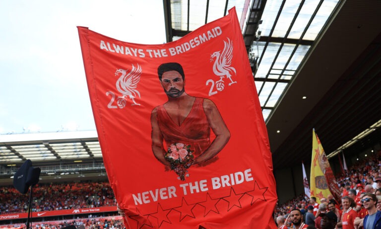 A Liverpool fan holds up a flag depicting an image of Arsenal manager Mikel Arteta with the text "always the bridesmaid, never the bride" prior to the Premier League match between Liverpool FC and Arsenal FC at Anfield on May 11, 2025 in Liverpool, England.