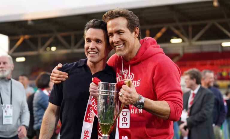 Rob McElhenney and Ryan Reynolds, co-owners of Wrexham AFC, pose for a photo with the trophy following the club's promotion to the Sky Bet Championship during the Sky Bet League One match between Wrexham AFC and Charlton Athletic FC at Racecourse Ground on April 26, 2025 in Wrexham, Wales.