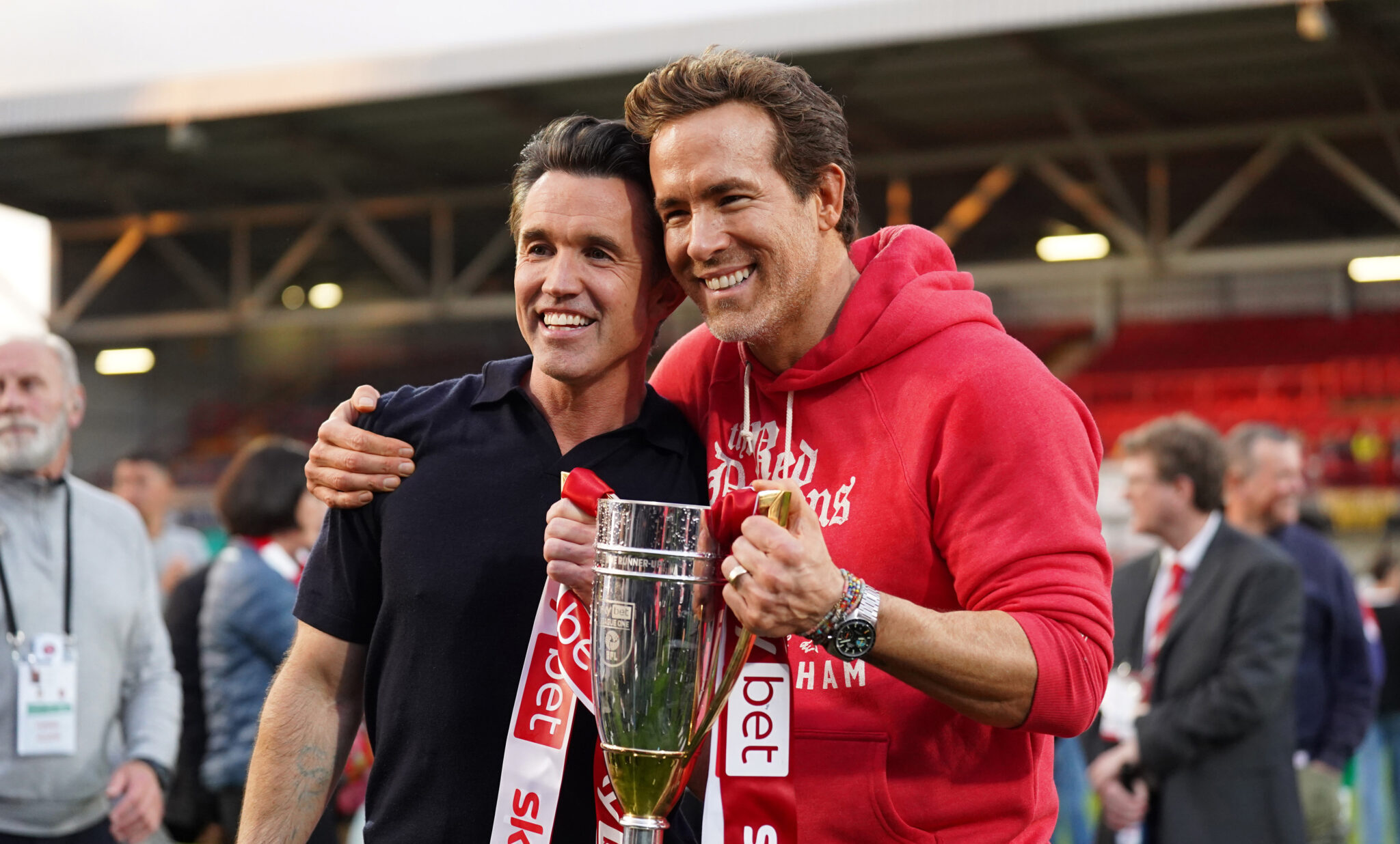 Rob McElhenney and Ryan Reynolds, co-owners of Wrexham AFC, pose for a photo with the trophy following the club's promotion to the Sky Bet Championship during the Sky Bet League One match between Wrexham AFC and Charlton Athletic FC at Racecourse Ground on April 26, 2025 in Wrexham, Wales.