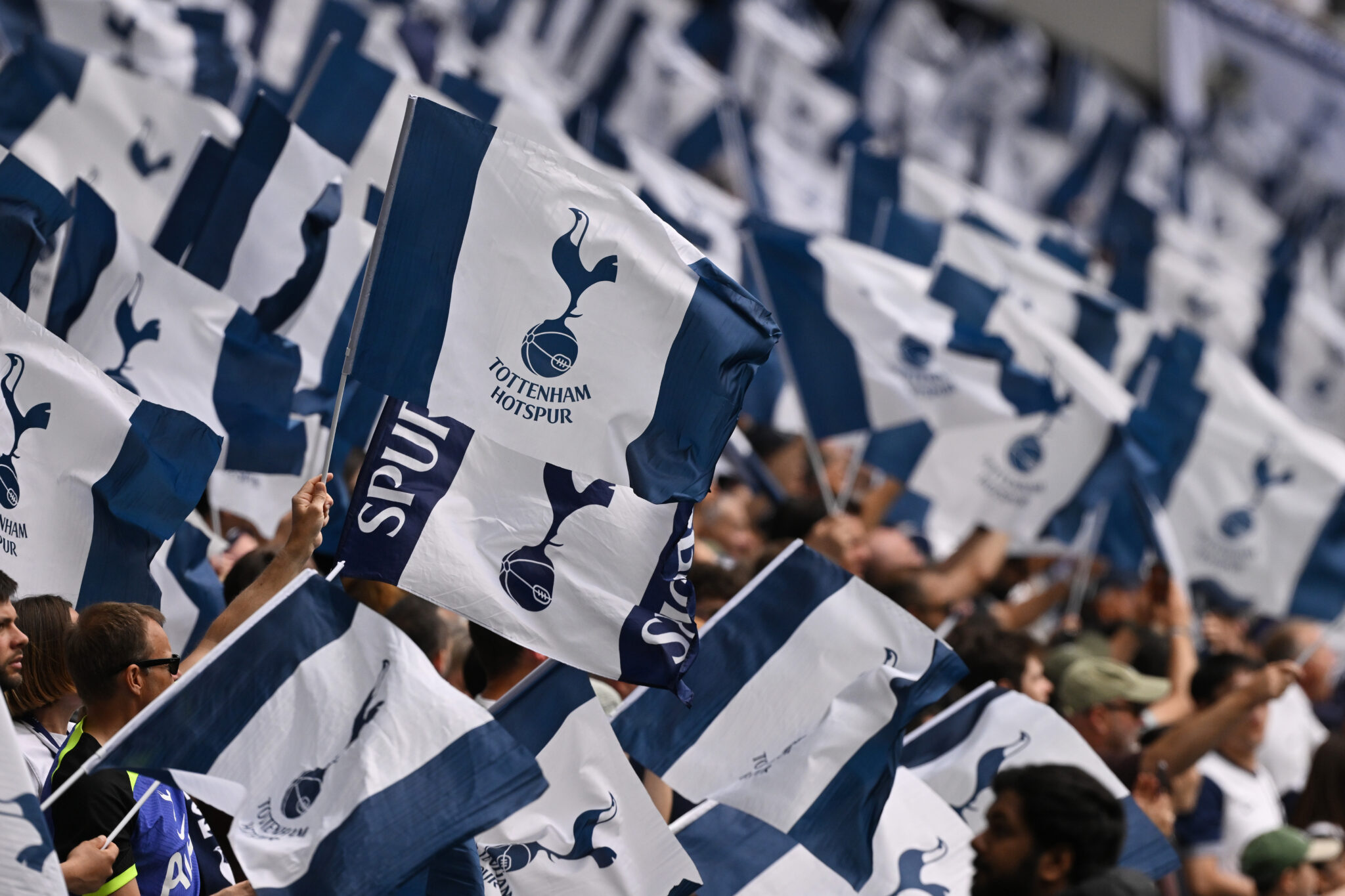 Spurs fans wave small flags in the stands prior to the Premier League match between Tottenham Hotspur FC and Brighton & Hove Albion FC at Tottenham Hotspur Stadium on May 25, 2025 in London, England.
