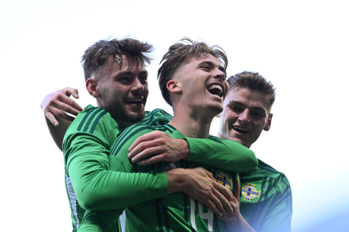 Isaac Price of Northern Ireland celebrates scoring his team's first goal with teammate Conor Bradley and Justin Devenny during the international friendly match between Northern Ireland and Iceland at Windsor Park on June 10, 2025 in Belfast, Northern Ireland.