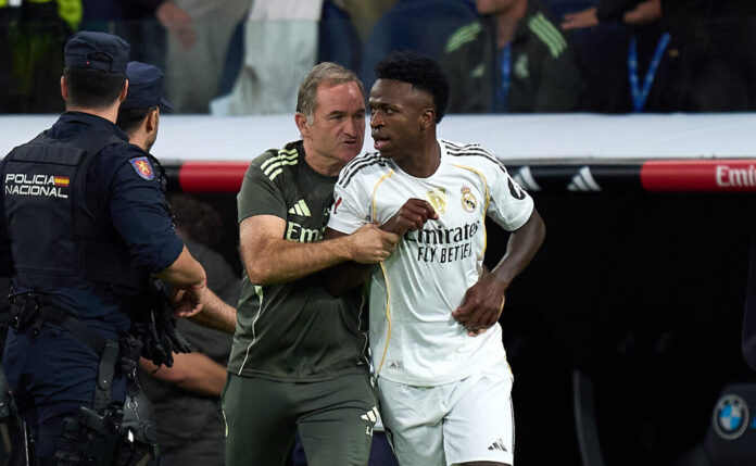 Vinicius Jr of Real Madrid is escorted off the pitch by Luis Llopis, goalkeeper coach of Real Madrid, after the LaLiga EA Sports match between Real Madrid CF and FC Barcelona at Estadio Santiago Bernabeu on October 26, 2025 in Madrid, Spain.