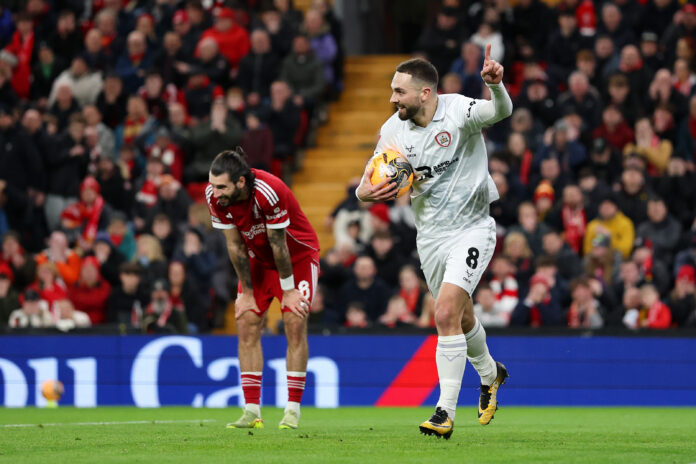 LIVERPOOL, ENGLAND - JANUARY 12: Adam Phillips of Barnsley celebrates scoring his team's second goal as Dominik Szoboszlai of Liverpool reacts after making a defensive error during the Emirates FA Cup Third Round match between Liverpool and Barnsley on January 12, 2026 in Liverpool, England.