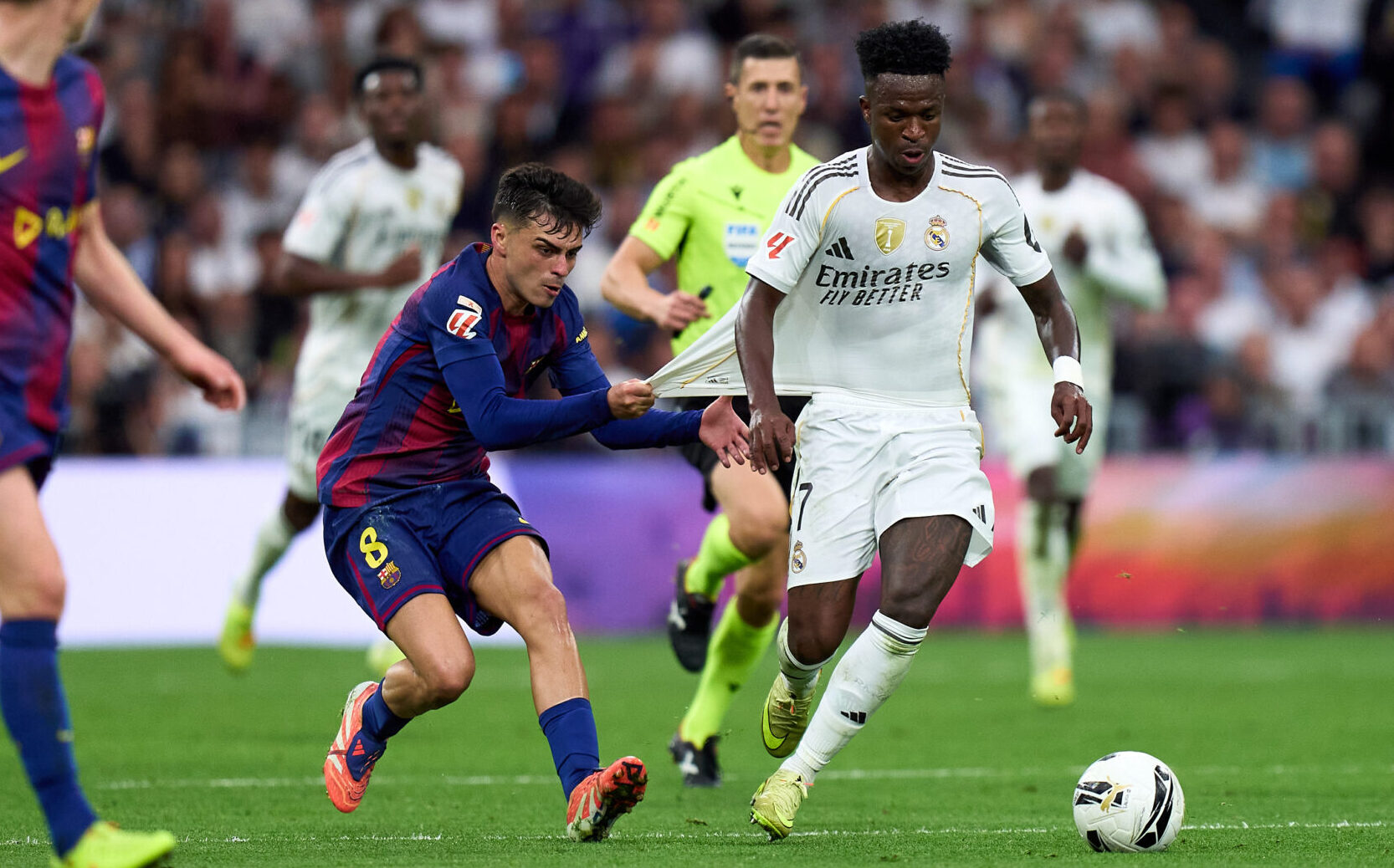 Vinicius Junior of Real Madrid is challenged by Pedri of FC Barcelona during the LaLiga EA Sports match between Real Madrid CF and FC Barcelona at Estadio Santiago Bernabeu on October 26, 2025 in Madrid, Spain.