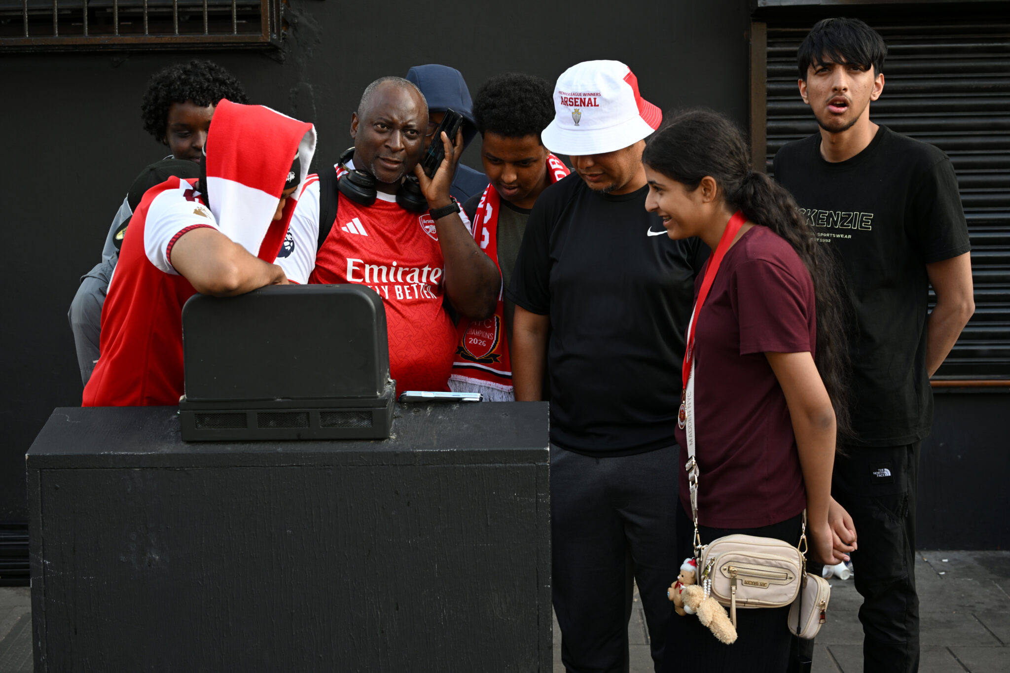 Arsenal fans gathered outside the Emirates stadium follow the match on their devices during the UEFA Champions League Final against PSG on May 30, 2026 in London, England.