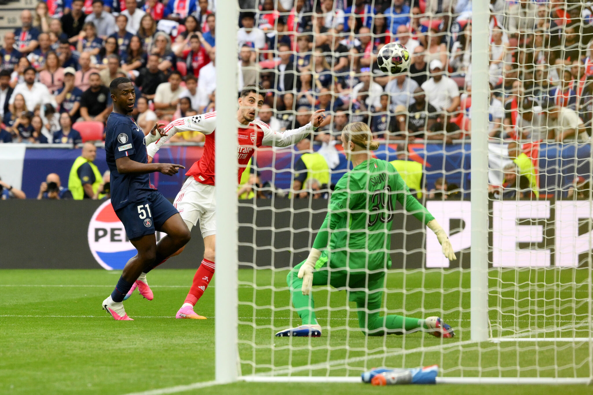 Kai Havertz of Arsenal scores his team's first goal while under pressure from William Pacho of Paris Saint-Germain during the UEFA Champions League Final 2026 match between Paris Saint-Germain and Arsenal FC at Puskas Arena on May 30, 2026 in Budapest, Hungary.